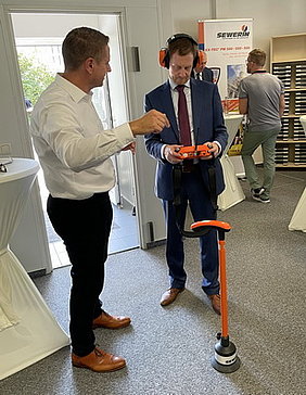 Michael Kersting (Hermann Sewerin GmbH) explains the latest water leak detection technology to MP Kretschmer (right).